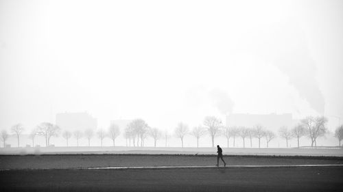 Man walking on field against foggy weather