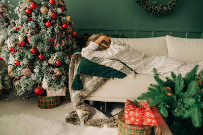 Upset sad depressed woman buried her head in pillow while lying on sofa in christmas. psychology.