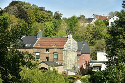 Houses by trees and buildings in town against sky
