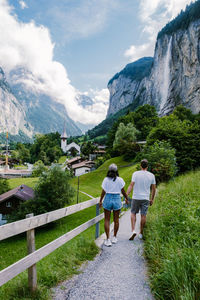 Rear view of people walking on mountain against sky