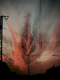Low angle view of silhouette electricity pylon against dramatic sky