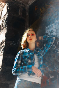 Beautiful young woman posing while standing against wall