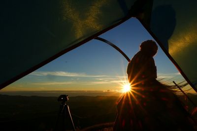 Silhouette man photographing at sunset