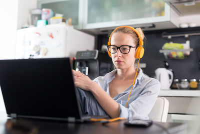 Mid adult business woman working on laptop at home