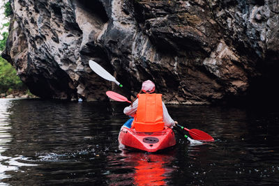 Woman canoeing in lake against rock formation