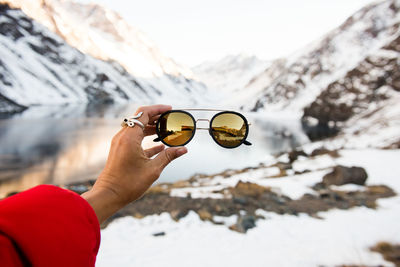 Midsection of person holding ice cream against snowcapped mountains