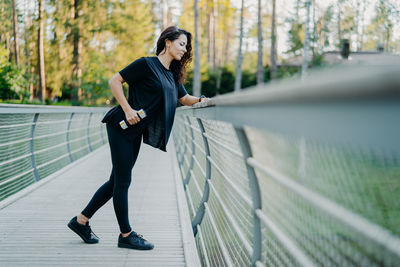 Woman exercising on footbridge in forest