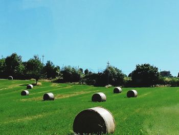 Hay bales on field against clear sky