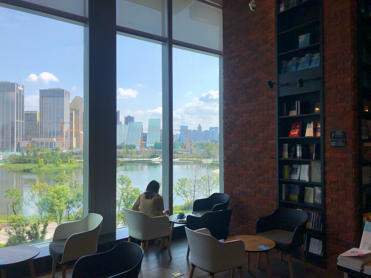 window, architecture, transparent, glass - material, chair, built structure, indoors, seat, table, city, day, building, people, office, business, sky, sitting, nature, skyscraper, coffee table, apartment