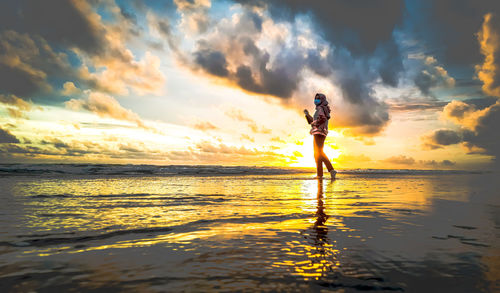 Full length of man standing at beach during sunset