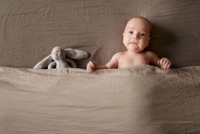 Portrait of baby boy with toy lying on bed