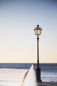 Street light by sea against clear sky