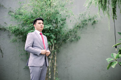 Portrait of young man standing against plants