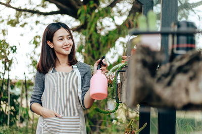 Portrait of smiling woman standing against plants