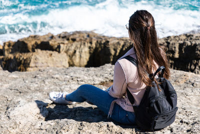 Rear view of woman sitting on rock