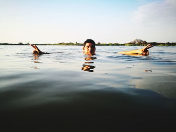 Portrait of man gesturing peace sign while swimming in lake