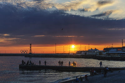 Silhouette people on beach against sky during sunset