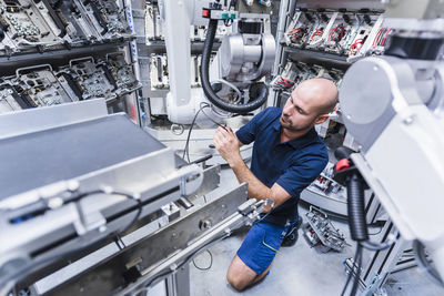 Man working at industrial robot in modern factory