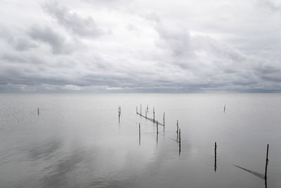 Wooden posts in sea against sky