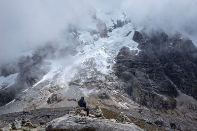 Man standing on rock against sky during winter