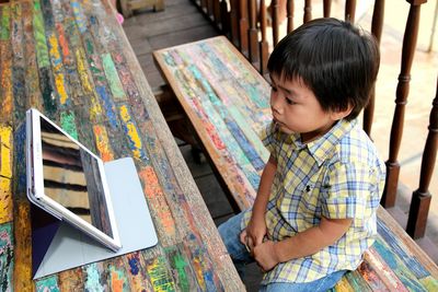 High angle view of boy looking at digital tablet on picnic table