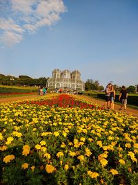 People on flowering plants against sky