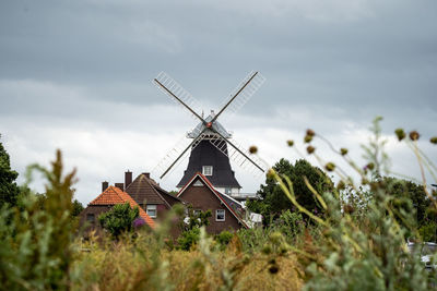 Traditional windmill by building against sky