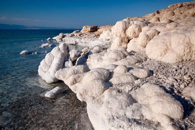 Rock formation on beach against sky