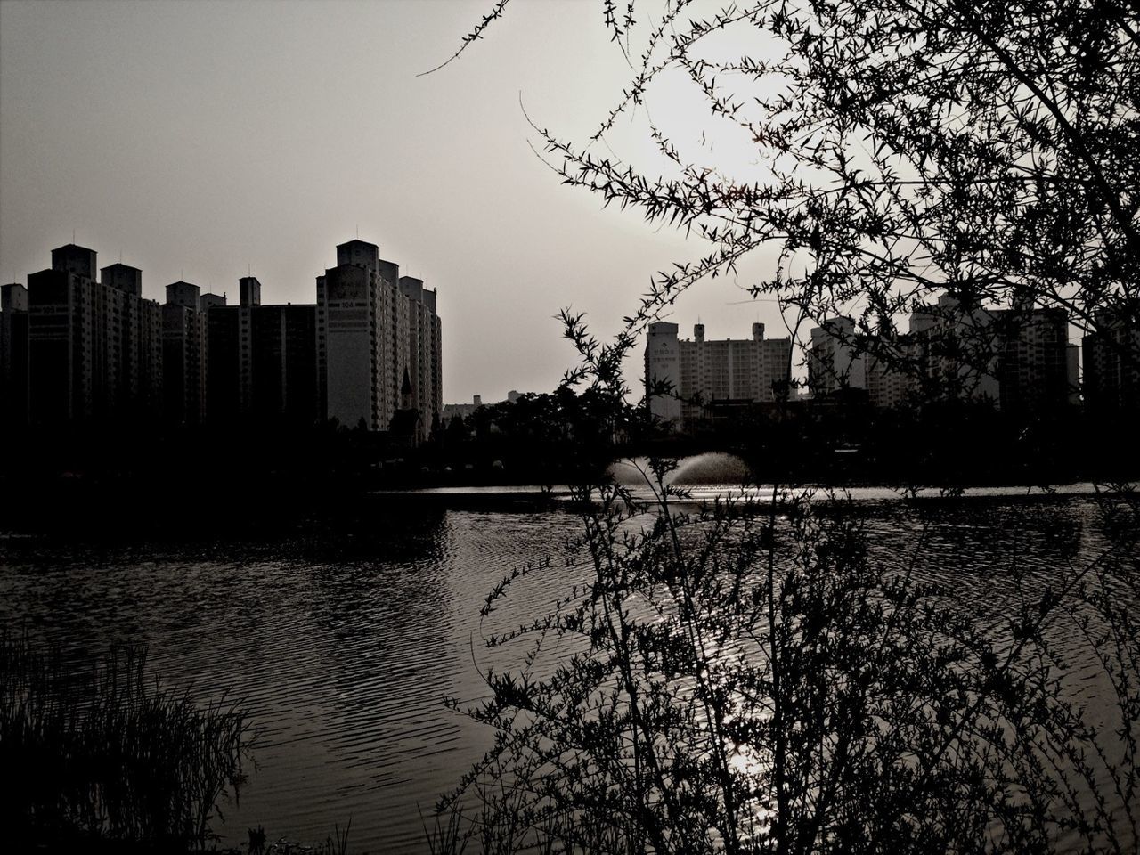 building exterior, water, architecture, built structure, city, reflection, river, waterfront, sky, tree, lake, silhouette, building, cityscape, sunset, bare tree, outdoors, skyscraper, residential building, no people