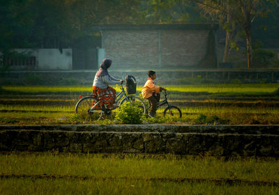 Woman riding bicycle with son on field