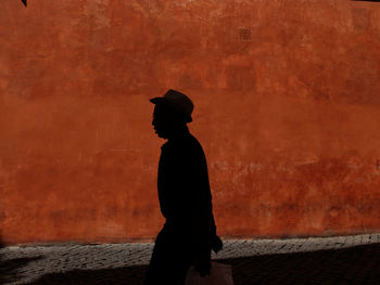 Silhouette man walking against wall