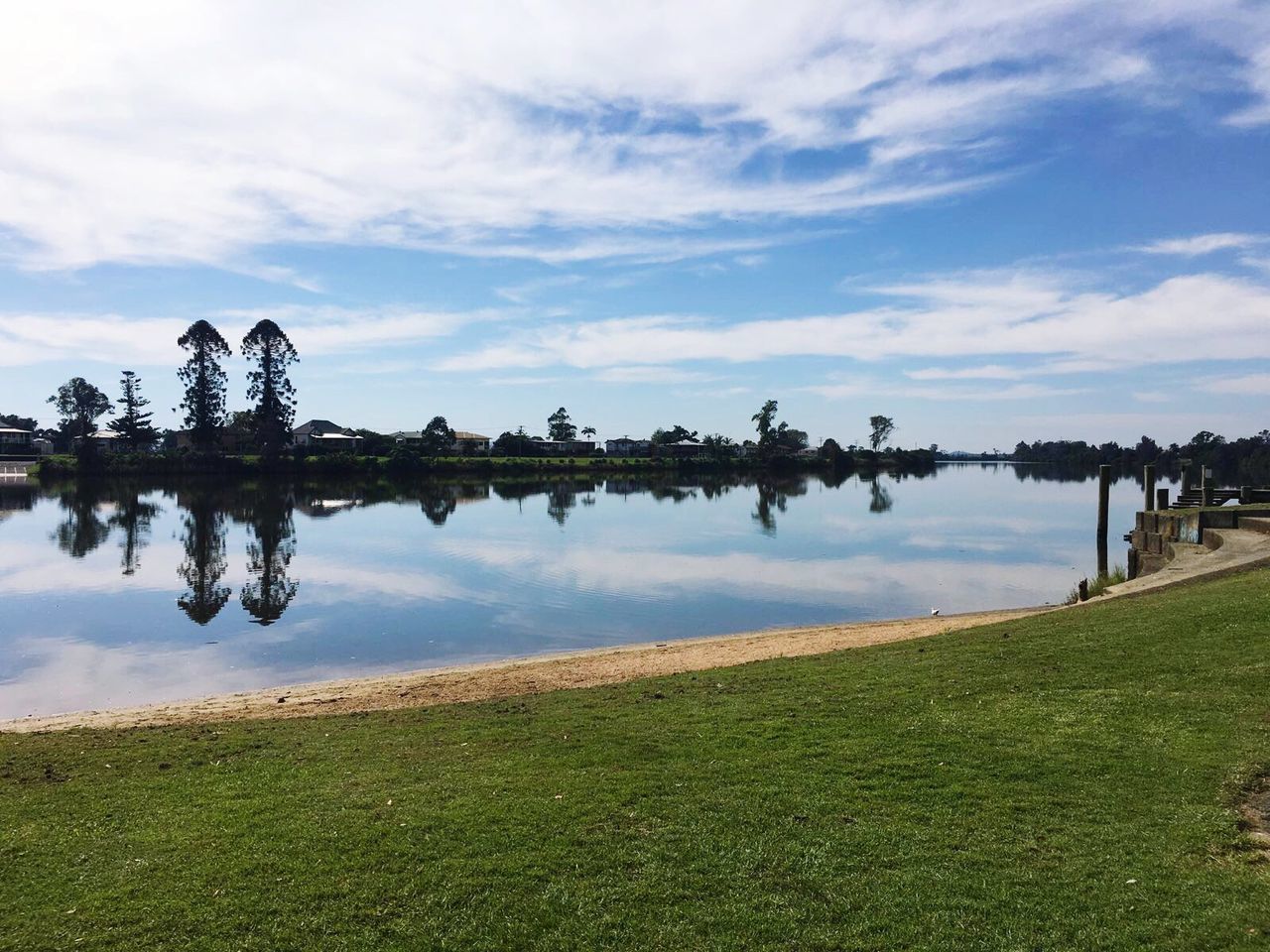 water, reflection, tranquil scene, tranquility, scenics, sky, lake, grass, palm tree, beauty in nature, tree, standing water, nature, calm, cloud - sky, day, blue, growth, tourism, non-urban scene, green color, no people, remote, majestic, shore, vacations