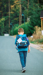 A boy with a satchel returns home from school