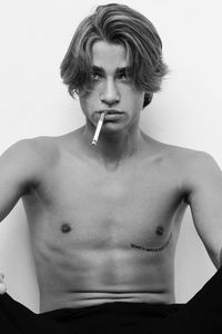 Portrait of shirtless man smoking against white background