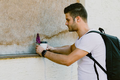 Side view of young man looking away against wall