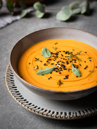 From above of bowl with delicious pumpkin soup served with seasonings on gray table in restaurant