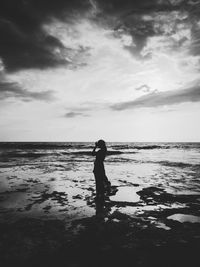 Silhouette woman standing on beach against sky