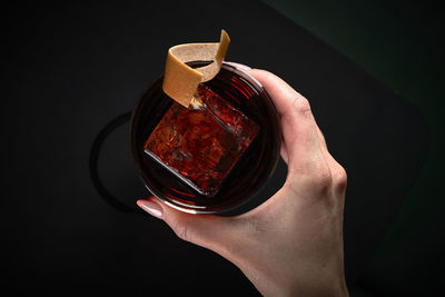 Cropped hand of woman holding crystal ball against black background