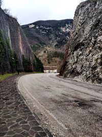 Road amidst trees and mountains against sky