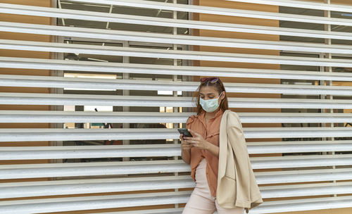 Young business woman wear face mask protect of coronavirus standing at modern office. covid-19