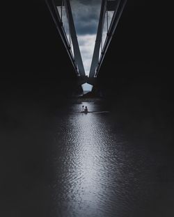 Silhouette bridge over river against sky