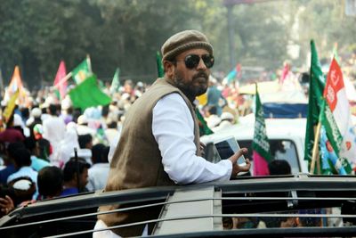 Man wearing sunglasses with mobile phone standing in car during protest