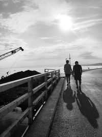 Rear view of people walking on bridge