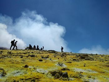 People on mountain against cloudy sky