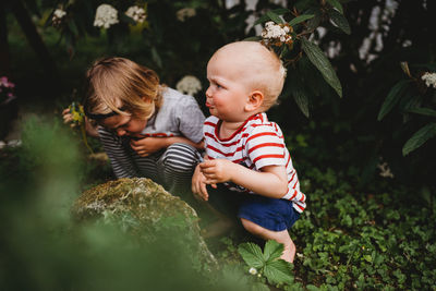 Blonde boys playing in the backyard barefoot searching for bugs barefoot