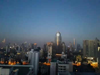 Illuminated buildings in city against clear sky