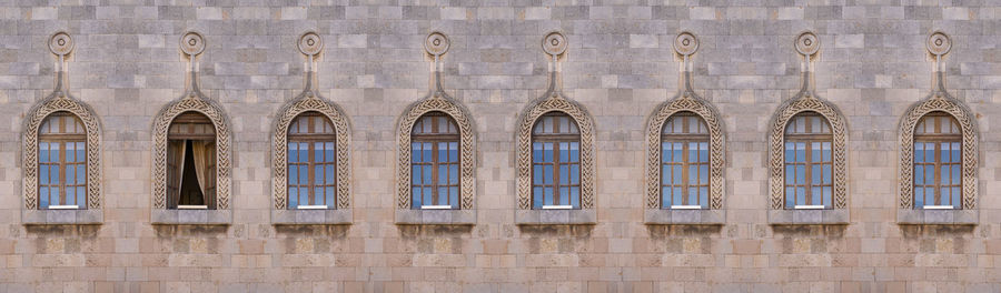 Wooden antique arch windows in a row all closed only one is open.