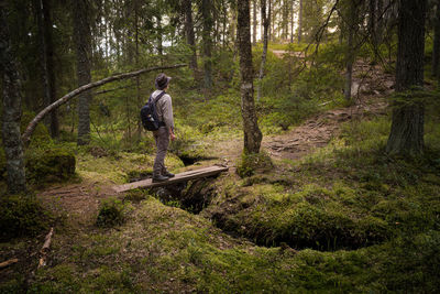 Man crossing a footbridge while hiking in a natural forest