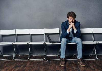 Full length of young man sitting on chair