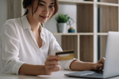 Midsection of woman using mobile phone while sitting on table